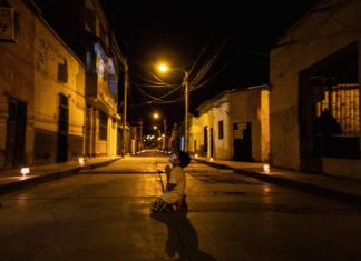 Criança reza de joelhos na rua pelo fim do coronavírus, durante toque de recolher no Peru